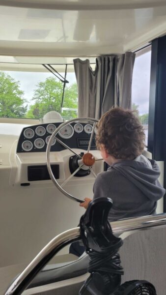 A child sitting at steering wheel of boat