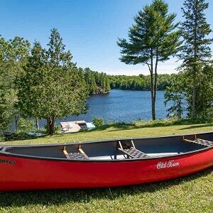 A canoe sits on land near the edge of a lake