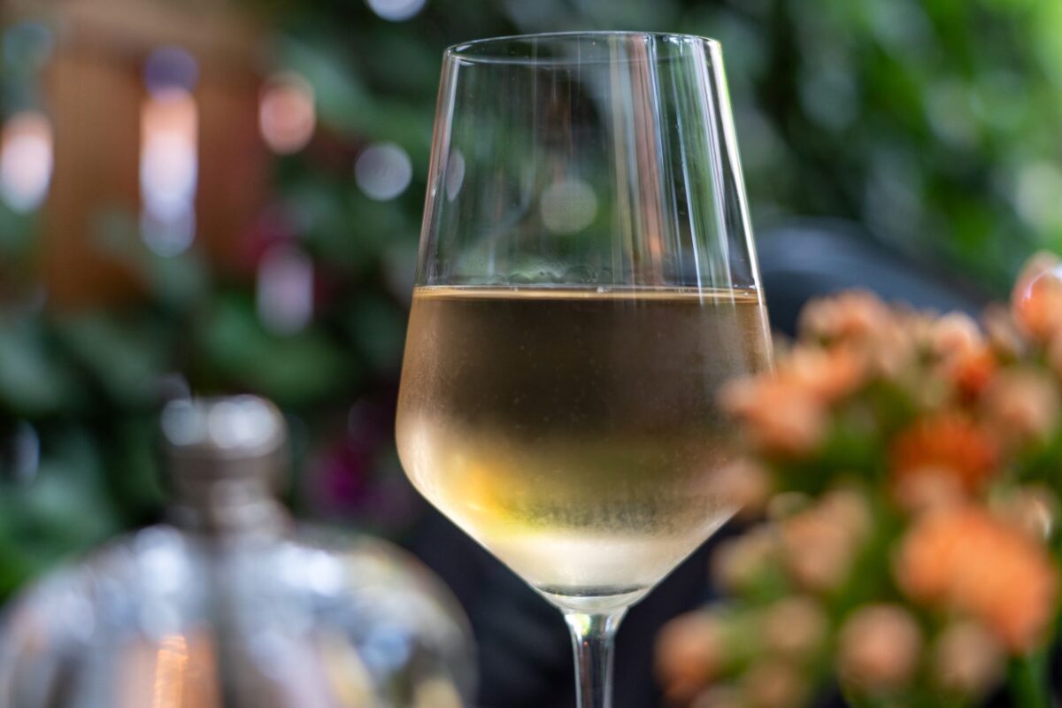 A glass of wine near flowers.