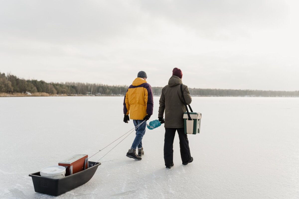 Couple walking on the lake to go ice fishing. A great activity during your Haliburton cottage rental