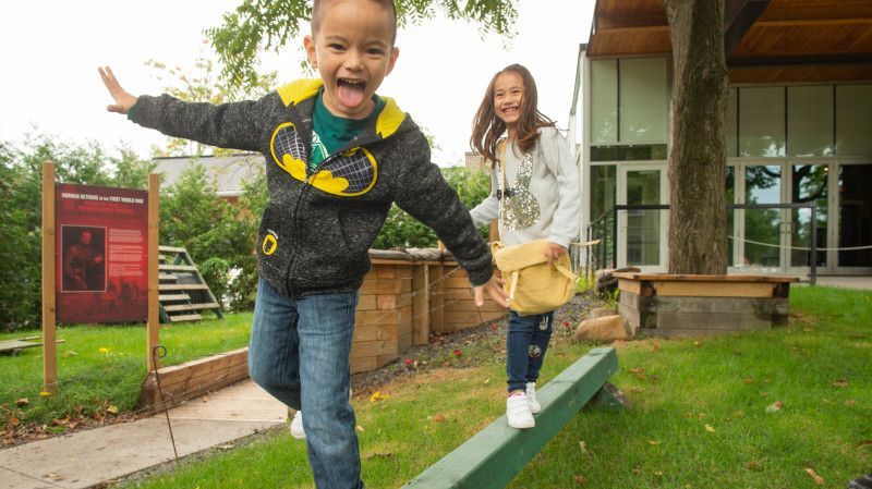 Kids walking on an outdoor balance beam at Bethune Memorial House Kidzone - Muskoka